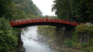 Kızıl Shinkyo köprüsü Nikko 'da fırtınalı bir nehirde, yağmurlu bir günde, Japonya' da.