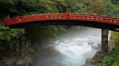 Kızıl Shinkyo köprüsü Nikko 'da fırtınalı bir nehirde, yağmurlu bir günde, Japonya' da.