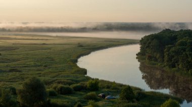 Camping with cars and summer morning fog over the river in the Voronezh region, nature of Russia. clipart