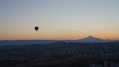 Türkiye 'nin Merkez Anadolu kentindeki Kapadokya' da gün doğumunda açık gökyüzünde uçan sıcak hava balonunun silüeti.      