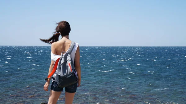 Girl with a backpack and a T-shirt which falling off her shoulder, Black Sea, Russiaj.