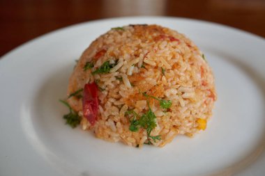 Beyaz tabakta sebzeli baharatlı pilav, restoranda akşam yemeği..   