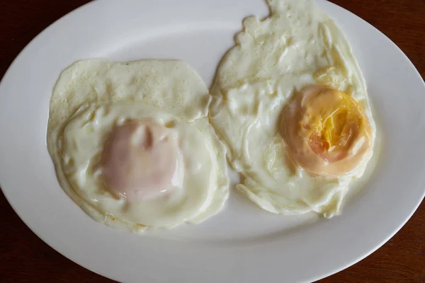 Två Stekta Ägg Till Frukost Vit Tallrik Ett Träbord — Stockfoto