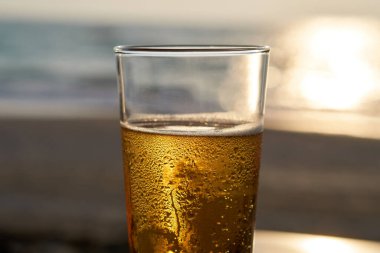 Gün batımında soğuk bira, arka planda deniz ve plaj..