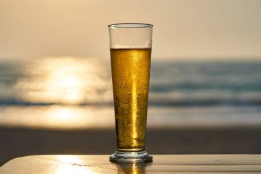 Gün batımında soğuk bira, arka planda deniz ve plaj..