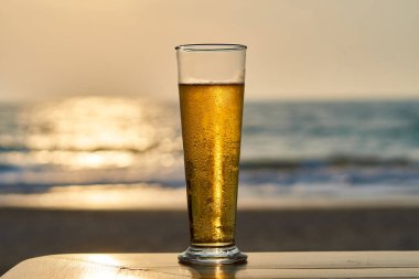Gün batımında soğuk bira, arka planda deniz ve plaj..