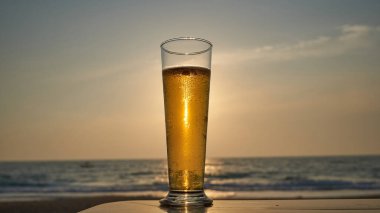 Gün batımında soğuk bira, arka planda deniz ve plaj..