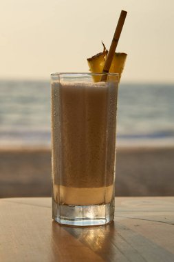 Gün batımında Pina Colada kokteyli, arka planda deniz ve plaj..