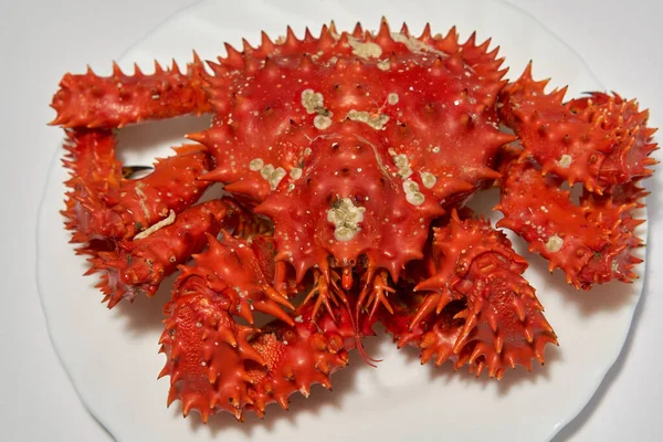 Raw Kamchatka red king crab on a white plate.