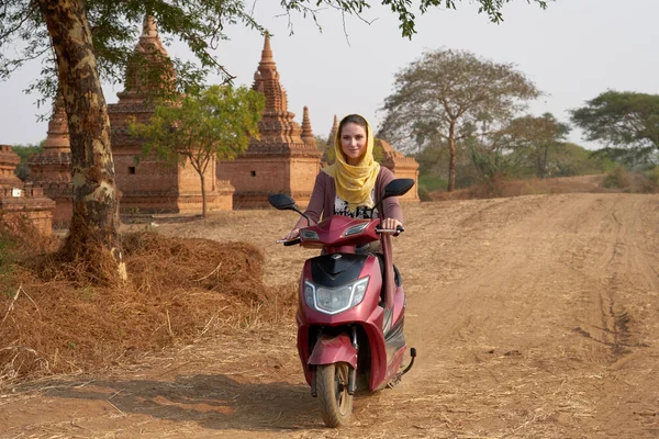 A woman travels on an electric bike through ancient temples in old Bagan in Myanmar.