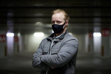 Siyah maskeli bir adam salgın sırasında ve Rusya 'daki yeraltı otoparkında gri ceketli bir adamdan kendini korumak için..