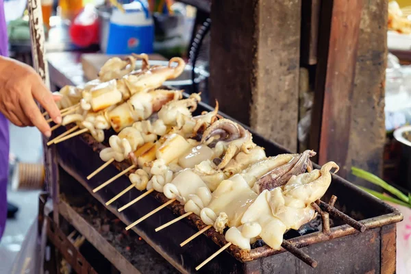 Squid on skewers is being grilled by a street vendor — Stock Photo, Image