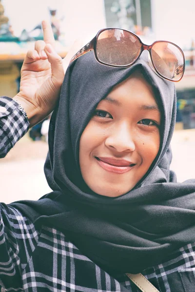 Nuori nainen hijabissa hymyilee ja aiheuttaa kameran — kuvapankkivalokuva