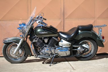 Yamaha Dragstar 1100 motosiklet garajın önünde
