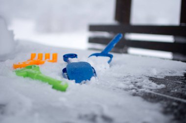 Masadaki oyuncaklar karla kaplı. Arka planda karla kaplı bir dağ. İlk mavi oyuncağa odaklan..