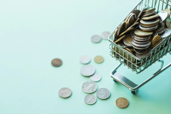 Shopping cart full of coins over the green background — Stock Photo, Image