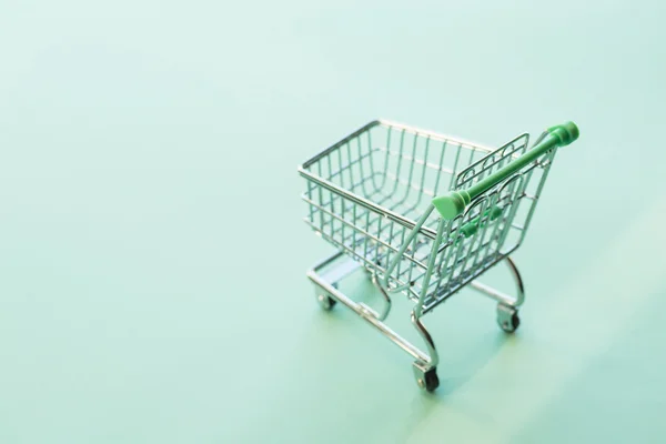 Carro de compras vacío sobre el fondo verde —  Fotos de Stock