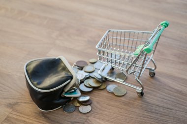 M-cüzdan ve ahşap masa üzerinde para ile alışveriş sepeti