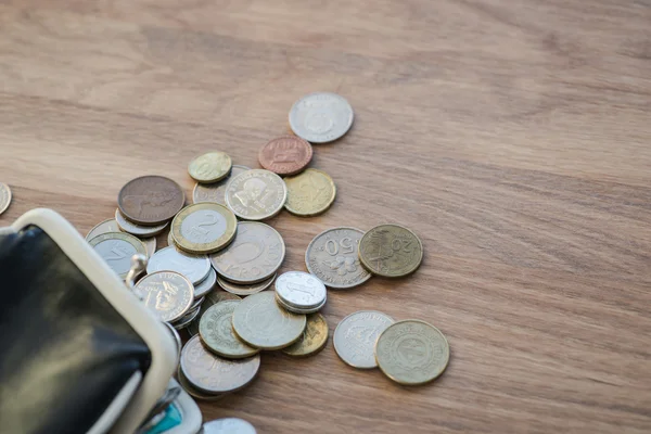 Black leather wallet with different coins on the wooden surface — Stock Photo, Image