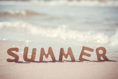 Yaz. Kum üzerinde ahşap harfler