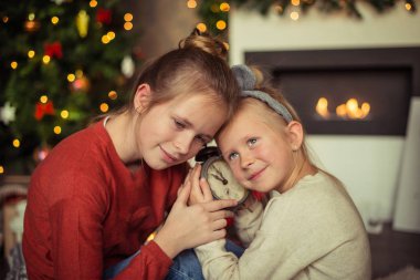 Noel. İki kız kardeş dinler için saat şöminenin yanında