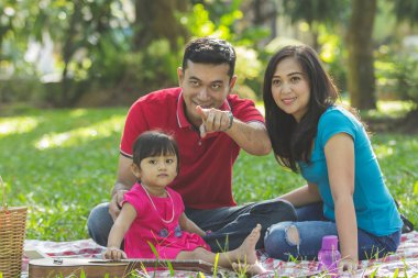 Açık havada aile portre kavramı. Ailesinin önünde bir şey, onun parmak işaret baba.