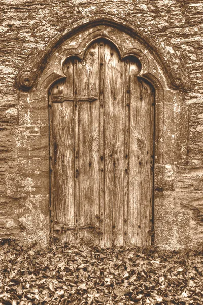 Puerta de madera medieval antigua con arco decorativo y hojas de otoño —  Fotos de Stock