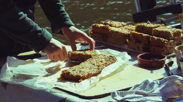 Frauenhände schneiden Kuchen am Stand der Marktbäckerei — Stockfoto