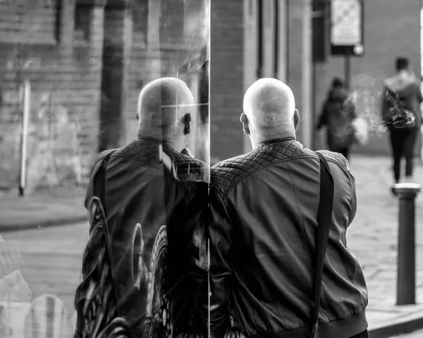 Man leunt tegen etalage waarin zijn spiegelbeeld — Stockfoto