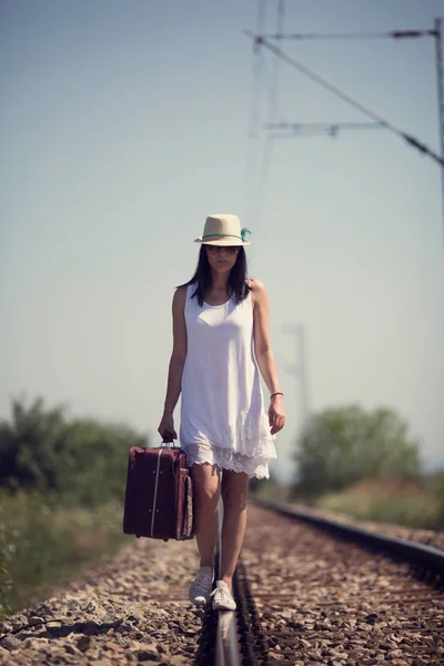 Femme marchant sur les voies ferrées avec une valise rétro — Photo