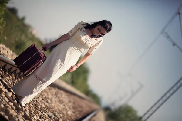 Femme sur voie ferrée avec une valise rétro — Photo
