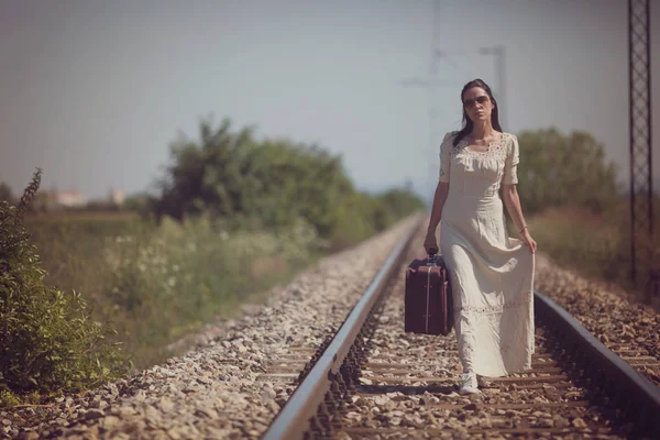 Mulher em trilhos ferroviários com uma mala retro — Fotografia de Stock