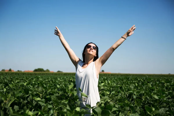Женщина, протягивая руки, чувствует себя счастливой в поле — стоковое фото