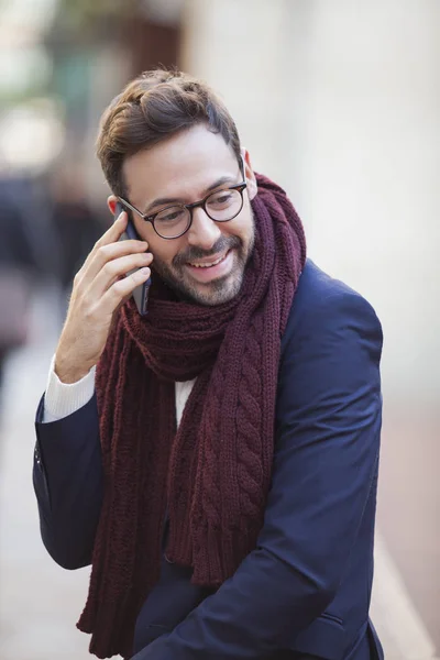 Handsome stylish man talking on the phone and smiling in the city