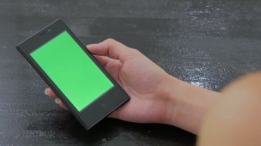 Yeşil ekranlı akıllı telefona bakan kadın