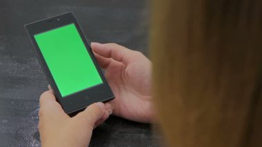 Yeşil ekranlı akıllı telefona bakan kadın
