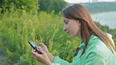 Güzel kız nehrin telefon ile dolgu üzerinde ayakta