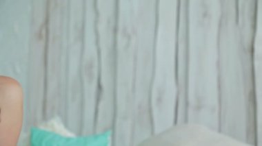 Genç kıvırcık kadın yatakta tablet pc ile oturuyordu. Dolly vurdu