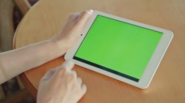Kafede yeşil ekranlı tablet bilgisayar arayan kadın