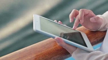Tablet cruise gemi güvertesinde güneş doğarken kullanan kadın