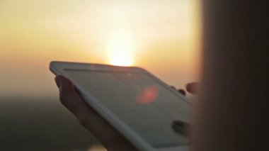 Gün batımında dijital tablet ile kadın el