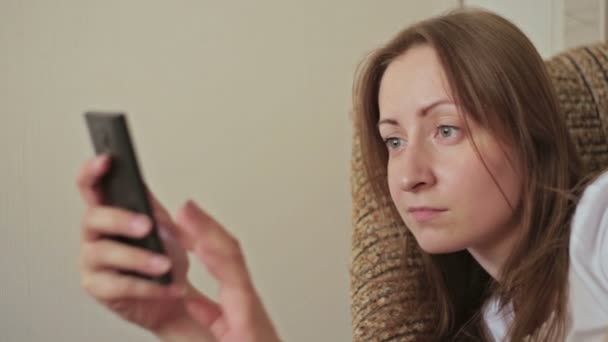 Mujer joven usando el teléfono móvil en casa — Vídeos de Stock
