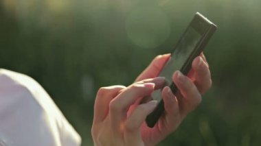 Kadın sms manifatura app günbatımında güneş objektif parlama ile akıllı telefon kullanarak