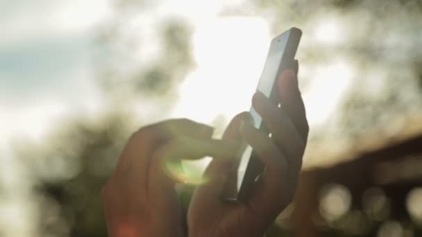 Silueta de manos de mujer con teléfono inteligente al atardecer — Vídeo de stock