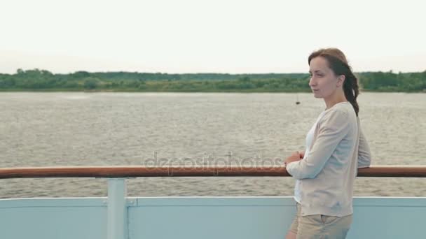 Jovem mulher bonita de pé no convés do navio de cruzeiro e olhando para o rio . — Vídeo de Stock