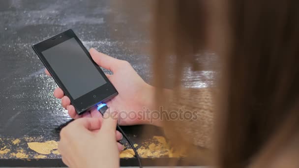 Womans hand plugging black lightning charging cable into smartphone — Stock Video