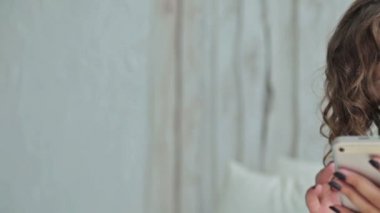 Genç kıvırcık kadın yatakta tablet pc ile oturuyordu. Dolly vurdu