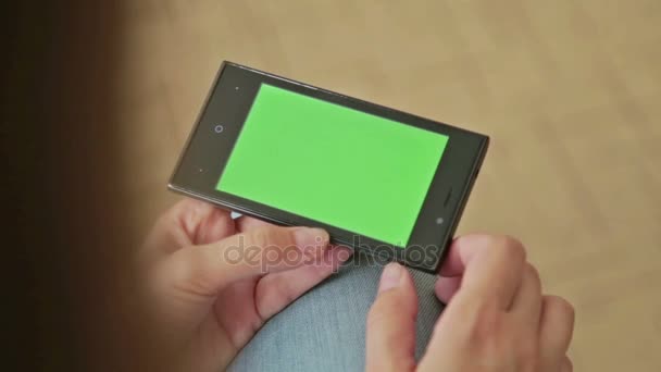 Mujer bonita sosteniendo en la mano teléfono inteligente con pantalla verde — Vídeos de Stock