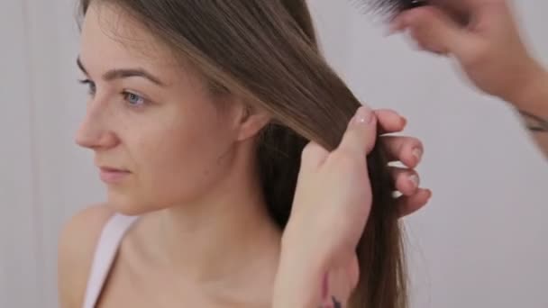 Um tiro de perto. Cabeleireiro profissional fazendo penteado para jovem mulher bonita com cabelo longo — Vídeo de Stock