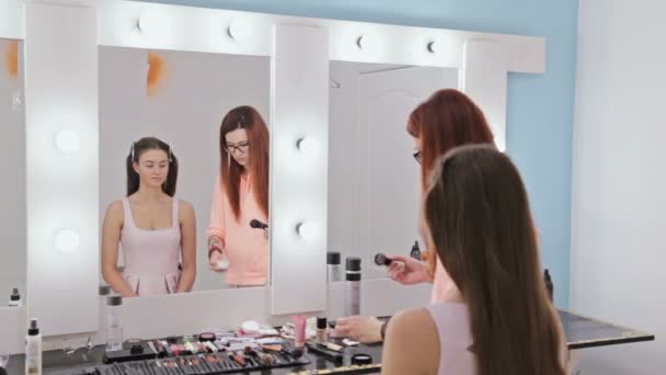 2 βολές. Επαγγελματία make-up artist εφαρμογή πούδρας στο πρόσωπο γυναίκας — Αρχείο Βίντεο